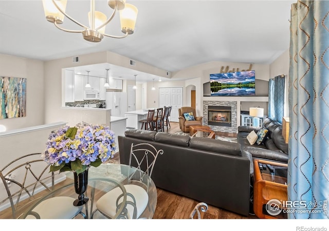 1703 Whitehall Dr Unit G, Longmont, CO 80504 - living area with wood finished floors, a stone fireplace, a chandelier, and lofted ceiling