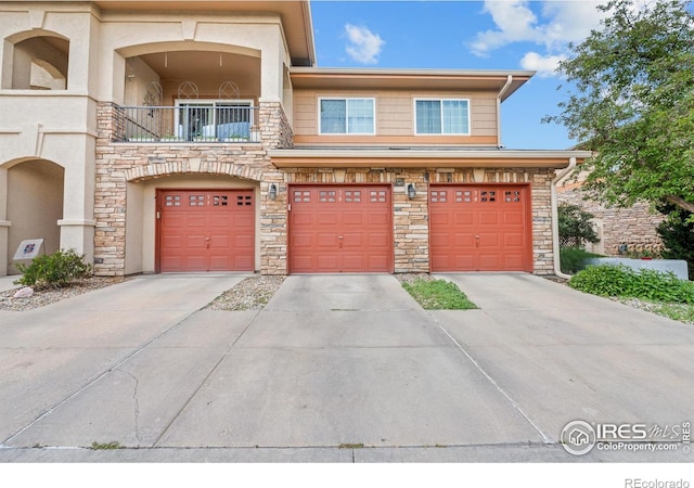 1703 Whitehall Dr Unit G, Longmont, CO 80504 - view of front facade with driveway, stone siding, a garage, and a balcony
