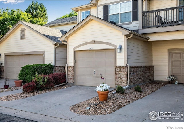 4672 W 20th Street Rd Unit 1311, Greeley, CO 80634 - view of front of home with brick siding, a balcony, driveway, an attached garage, and roof with shingles
