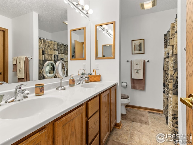 1316 Kinnikinnic Ct, Estes Park, CO 80517 - bathroom featuring double vanity, stone finish flooring, and a textured ceiling
