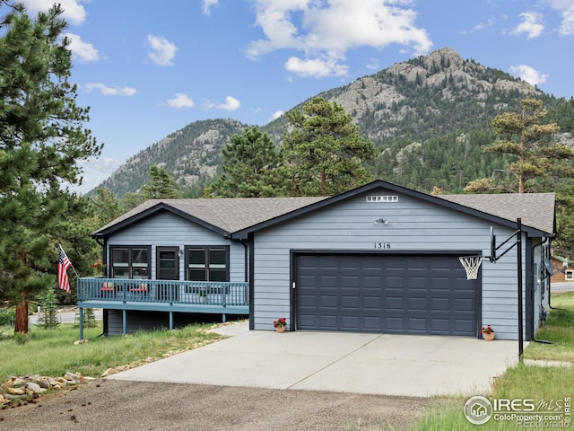 1316 Kinnikinnic Ct, Estes Park, CO 80517 - ranch-style home with a garage, driveway, roof with shingles, and a deck with mountain view