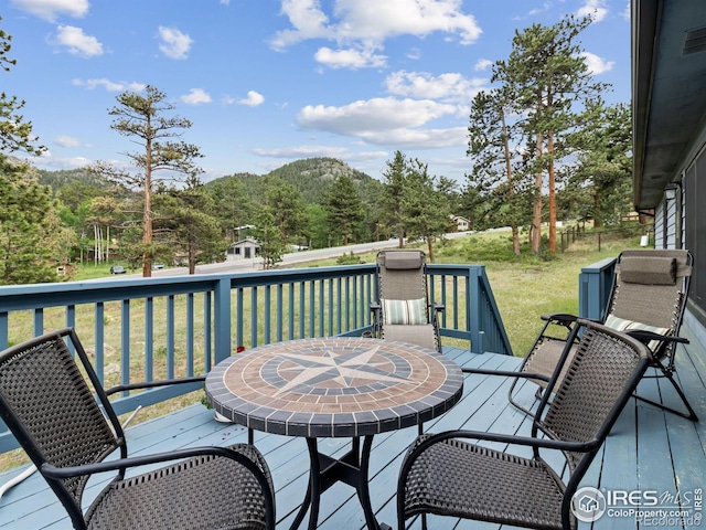 1316 Kinnikinnic Ct, Estes Park, CO 80517 - wooden deck featuring a lawn, outdoor dining area, and a forest view