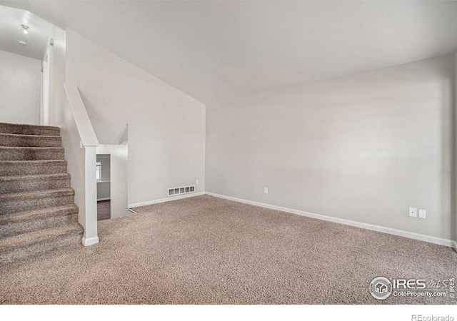 1634 San Juan Cir, Evans, CO 80620 - unfurnished living room with carpet, vaulted ceiling, and stairway