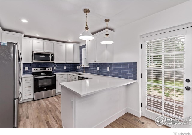 8696 W 86th Cir, Arvada, CO 80005 - kitchen featuring stainless steel appliances, a peninsula, light wood-style floors, white cabinets, and light countertops