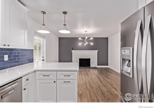 8696 W 86th Cir, Arvada, CO 80005 - kitchen with appliances with stainless steel finishes, a peninsula, light wood finished floors, white cabinets, and backsplash