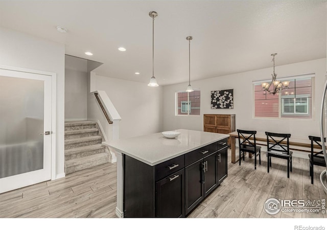 619 Brennan Cir, Erie, CO 80516 - kitchen featuring dark cabinets, light wood-type flooring, light countertops, a chandelier, and pendant lighting