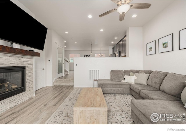 619 Brennan Cir, Erie, CO 80516 - living area with light wood finished floors, recessed lighting, a ceiling fan, a glass covered fireplace, and stairs