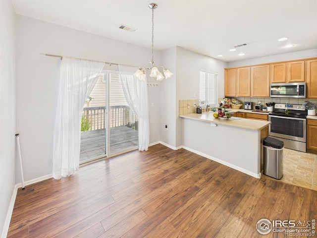 12912 Grant Cir E # A, Thornton, CO 80241 - kitchen featuring appliances with stainless steel finishes, wood finished floors, light countertops, a chandelier, and recessed lighting