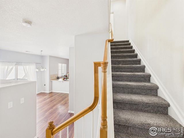 12912 Grant Cir E # A, Thornton, CO 80241 - stairway with wood finished floors, a chandelier, and a textured ceiling