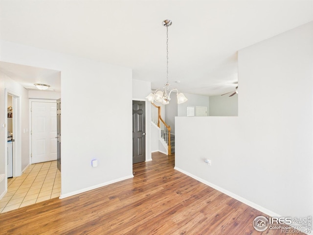 12912 Grant Cir E # A, Thornton, CO 80241 - empty room with light wood-style flooring, a ceiling fan, a chandelier, and stairs