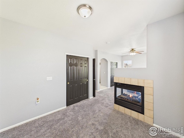 12912 Grant Cir E # A, Thornton, CO 80241 - unfurnished living room featuring arched walkways, carpet flooring, ceiling fan, and a tiled fireplace