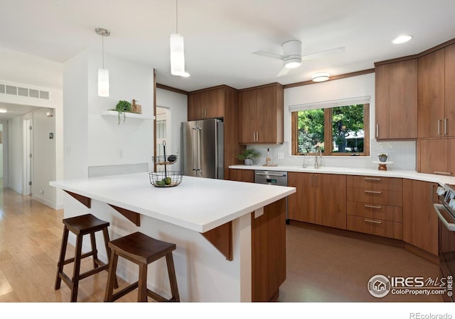 600 Monte Vista Ave, Fort Collins, CO 80521 - kitchen featuring stainless steel appliances, a breakfast bar, decorative backsplash, a peninsula, and brown cabinets