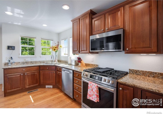 8305 E 149th Dr, Thornton, CO 80602 - kitchen with appliances with stainless steel finishes, light wood-style flooring, brown cabinetry, light stone counters, and recessed lighting