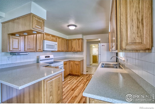 13600 Elmore Rd, Longmont, CO 80504 - kitchen with white appliances, backsplash, light wood finished floors, and a peninsula
