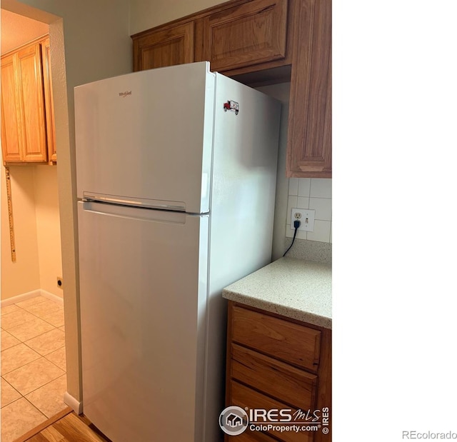 13600 Elmore Rd, Longmont, CO 80504 - kitchen with freestanding refrigerator, decorative backsplash, and light stone countertops