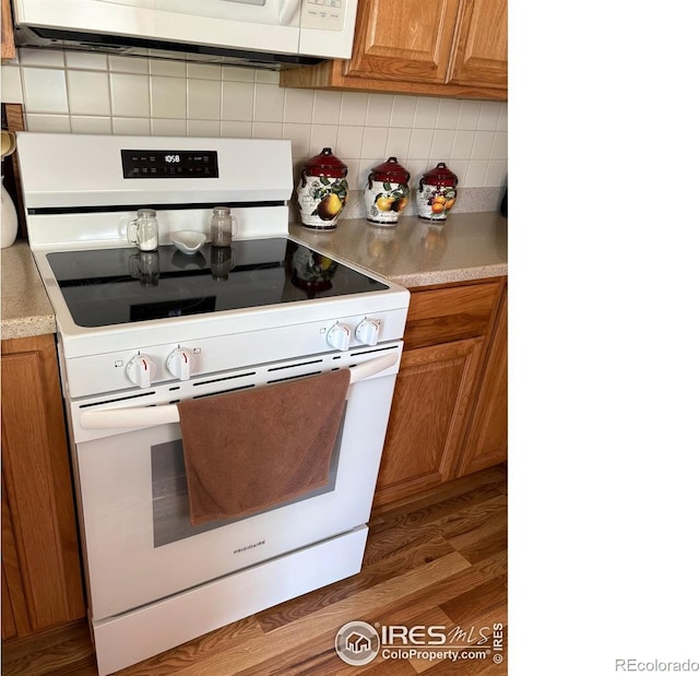 13600 Elmore Rd, Longmont, CO 80504 - kitchen featuring electric stove, brown cabinets, backsplash, and light countertops