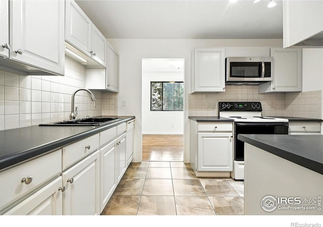 600 Manhattan Dr Unit B7, Boulder, CO 80303 - kitchen with stainless steel microwave, electric range, dark countertops, and white cabinets