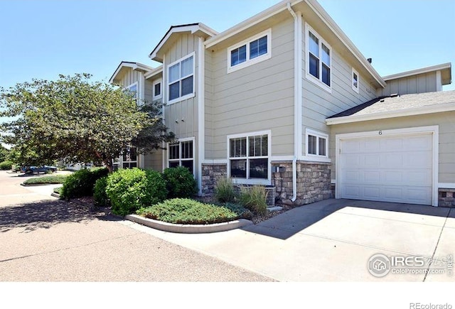 3641 29th St Unit 6, Greeley, CO 80634 - view of home's exterior with board and batten siding, driveway, an attached garage, and stone siding