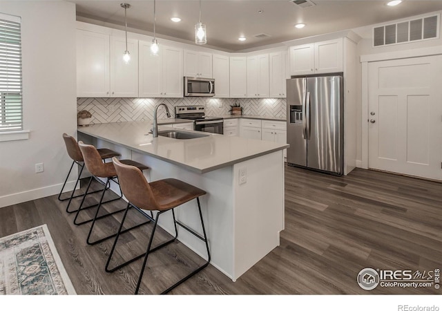 2402 49th Avenue Ct Unit 17, Greeley, CO 80634 - kitchen featuring stainless steel appliances, a kitchen bar, white cabinetry, backsplash, and a peninsula