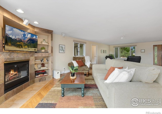 10947 Lynne Ave, Lafayette, CO 80026 - living area with wood finished floors, a tiled fireplace, recessed lighting, and built in features