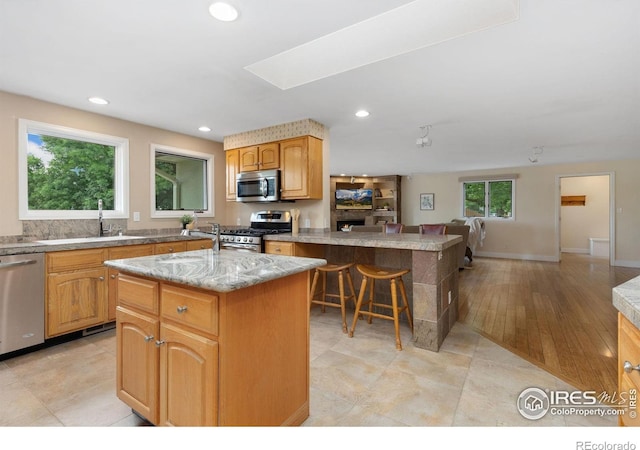 10947 Lynne Ave, Lafayette, CO 80026 - kitchen with appliances with stainless steel finishes, a center island, recessed lighting, a kitchen breakfast bar, and a peninsula