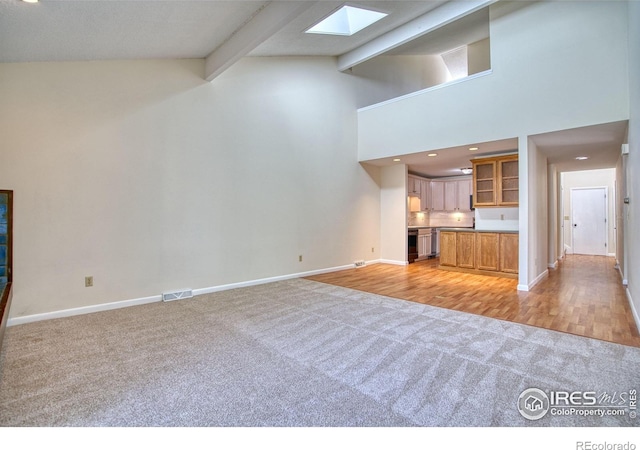 1925 28th Ave Unit 30, Greeley, CO 80634 - unfurnished living room featuring light carpet, beamed ceiling, a skylight, and high vaulted ceiling