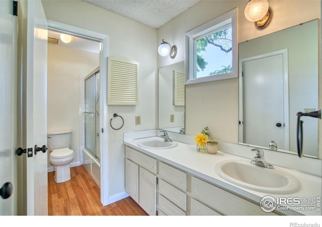 1925 28th Ave Unit 30, Greeley, CO 80634 - bathroom featuring wood finished floors, double vanity, enclosed tub / shower combo, and a textured ceiling