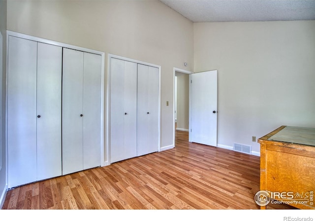 1925 28th Ave Unit 30, Greeley, CO 80634 - unfurnished bedroom featuring multiple closets, high vaulted ceiling, and light wood finished floors