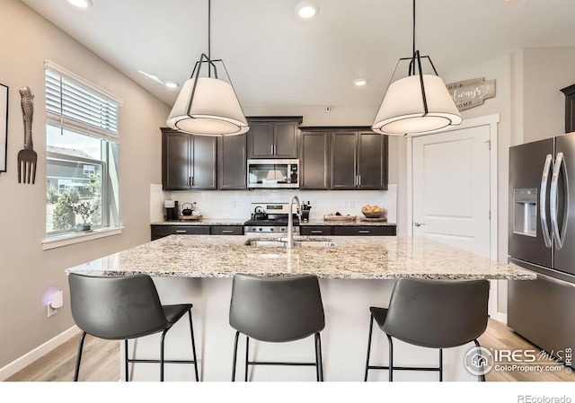 1591 Sun River Rd, Berthoud, CO 80513 - kitchen featuring appliances with stainless steel finishes, tasteful backsplash, light wood finished floors, a kitchen bar, and recessed lighting