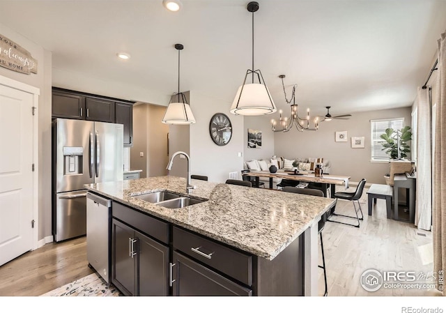1591 Sun River Rd, Berthoud, CO 80513 - kitchen featuring appliances with stainless steel finishes, an island with sink, light wood-type flooring, light stone countertops, and recessed lighting