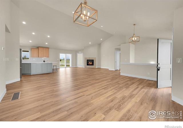 3643 Crested Owl Ct, Dacono, CO 80514 - unfurnished living room with vaulted ceiling, a chandelier, light wood finished floors, recessed lighting, and a tiled fireplace