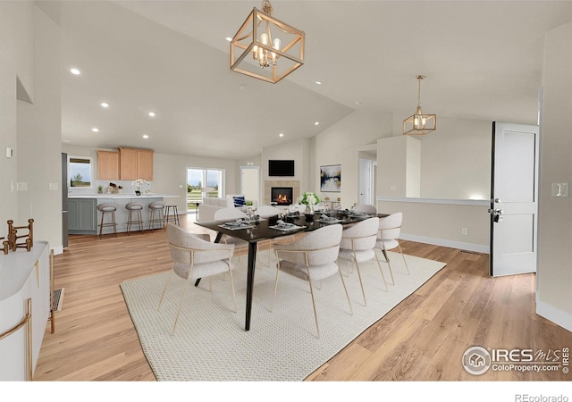 3643 Crested Owl Ct, Dacono, CO 80514 - dining space featuring recessed lighting, light wood-style flooring, a lit fireplace, a chandelier, and high vaulted ceiling