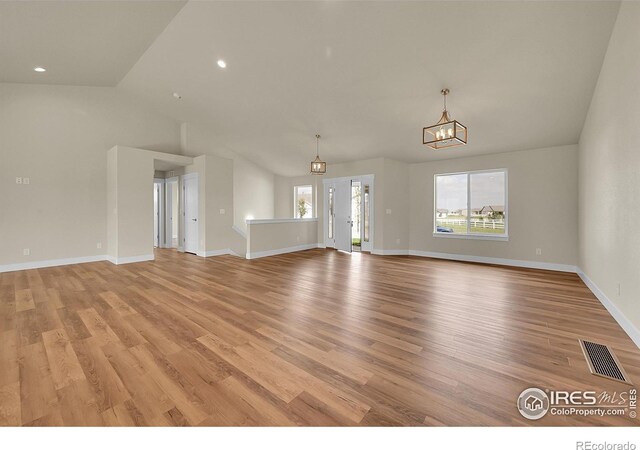 3643 Crested Owl Ct, Dacono, CO 80514 - unfurnished living room featuring light wood-type flooring, a chandelier, lofted ceiling, and recessed lighting