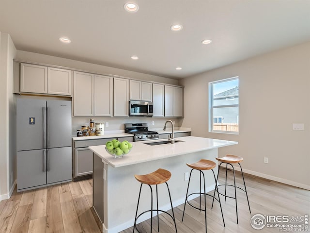 13 Chipeta Way, Lochbuie, CO 80603 - kitchen with appliances with stainless steel finishes, light wood-style floors, gray cabinets, a breakfast bar area, and light countertops