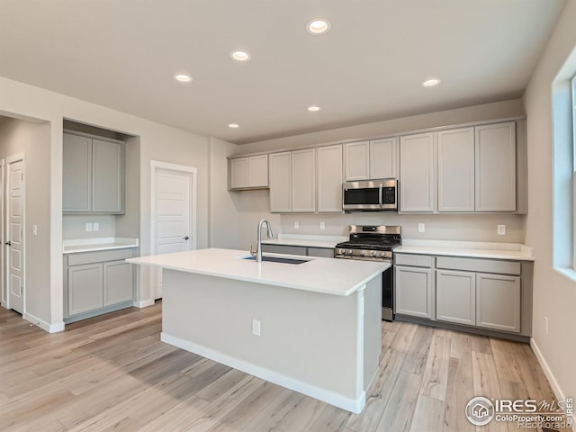 13 Chipeta Way, Lochbuie, CO 80603 - kitchen with stainless steel appliances, gray cabinets, light wood-style floors, light countertops, and a center island with sink