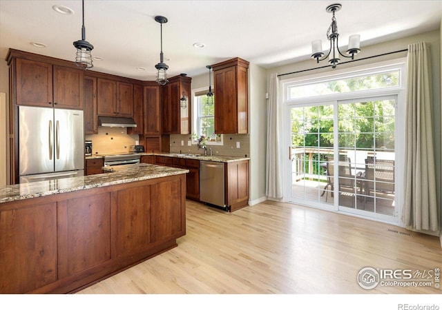 691 Tamarisk Ct, Louisville, CO 80027 - kitchen with stainless steel appliances, under cabinet range hood, a chandelier, light stone countertops, and recessed lighting