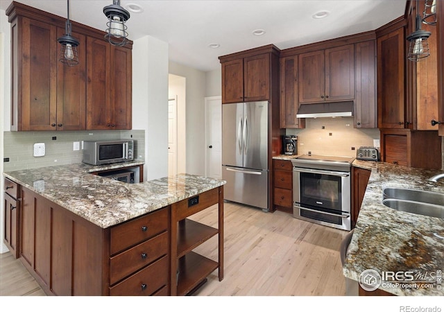 691 Tamarisk Ct, Louisville, CO 80027 - kitchen with stainless steel appliances, under cabinet range hood, light wood-style floors, tasteful backsplash, and recessed lighting