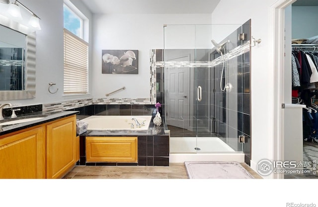 555 S 17th Ave, Brighton, CO 80601 - bathroom featuring a bath, vanity, a stall shower, a spacious closet, and wood finished floors