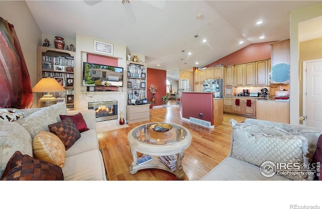 7294 Tamarisk Dr, Fort Collins, CO 80528 - living room with light wood-type flooring, ceiling fan, lofted ceiling, recessed lighting, and a tiled fireplace