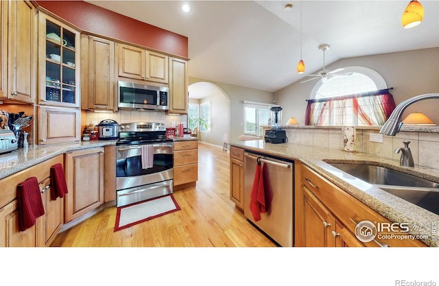 7294 Tamarisk Dr, Fort Collins, CO 80528 - kitchen with appliances with stainless steel finishes, light wood finished floors, arched walkways, tasteful backsplash, and vaulted ceiling