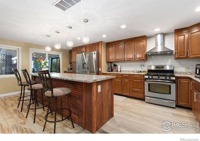 144 Placer Ave, Longmont, CO 80504 - kitchen with appliances with stainless steel finishes, wall chimney range hood, a kitchen island, backsplash, and a kitchen bar