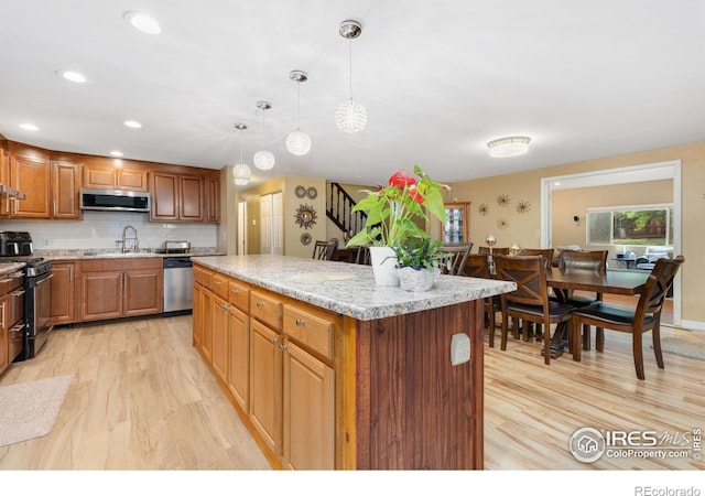 144 Placer Ave, Longmont, CO 80504 - kitchen with stainless steel appliances, light wood-style floors, a center island, and decorative backsplash