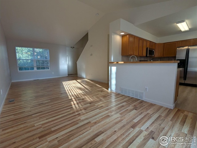 3705 Dove Ln, Evans, CO 80620 - kitchen with appliances with stainless steel finishes, open floor plan, light wood-style floors, lofted ceiling, and brown cabinets