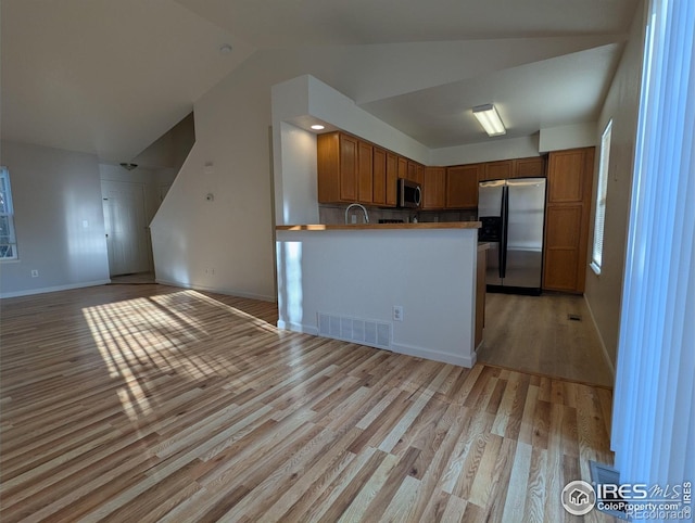 3705 Dove Ln, Evans, CO 80620 - kitchen featuring appliances with stainless steel finishes, lofted ceiling, light wood-type flooring, brown cabinetry, and open floor plan
