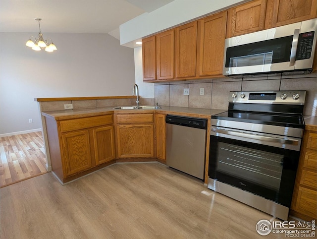 3705 Dove Ln, Evans, CO 80620 - kitchen featuring stainless steel appliances, light wood finished floors, a peninsula, brown cabinets, and a chandelier