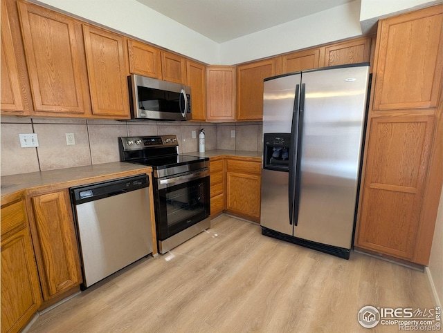 3705 Dove Ln, Evans, CO 80620 - kitchen with stainless steel appliances, light wood finished floors, decorative backsplash, and brown cabinets