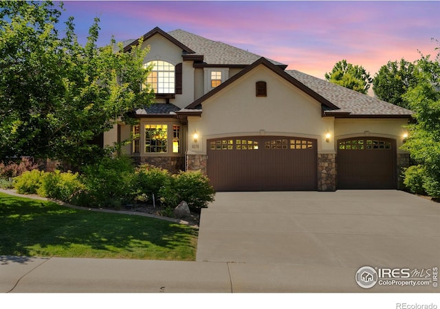 8276 Blackwood Dr, Windsor, CO 80550 - view of front of home featuring an attached garage, stone siding, concrete driveway, and stucco siding