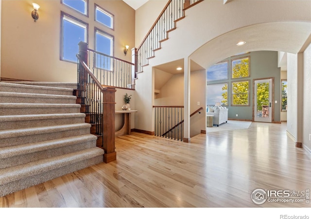 8276 Blackwood Dr, Windsor, CO 80550 - staircase featuring arched walkways, wood finished floors, and a high ceiling