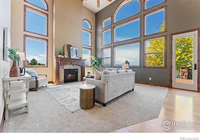 8276 Blackwood Dr, Windsor, CO 80550 - living room featuring a high ceiling, a warm lit fireplace, healthy amount of natural light, and a ceiling fan