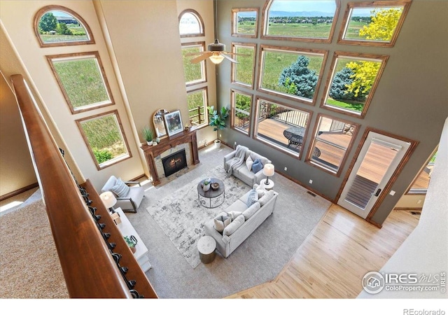8276 Blackwood Dr, Windsor, CO 80550 - living area featuring a towering ceiling, wood finished floors, a ceiling fan, and a fireplace with flush hearth